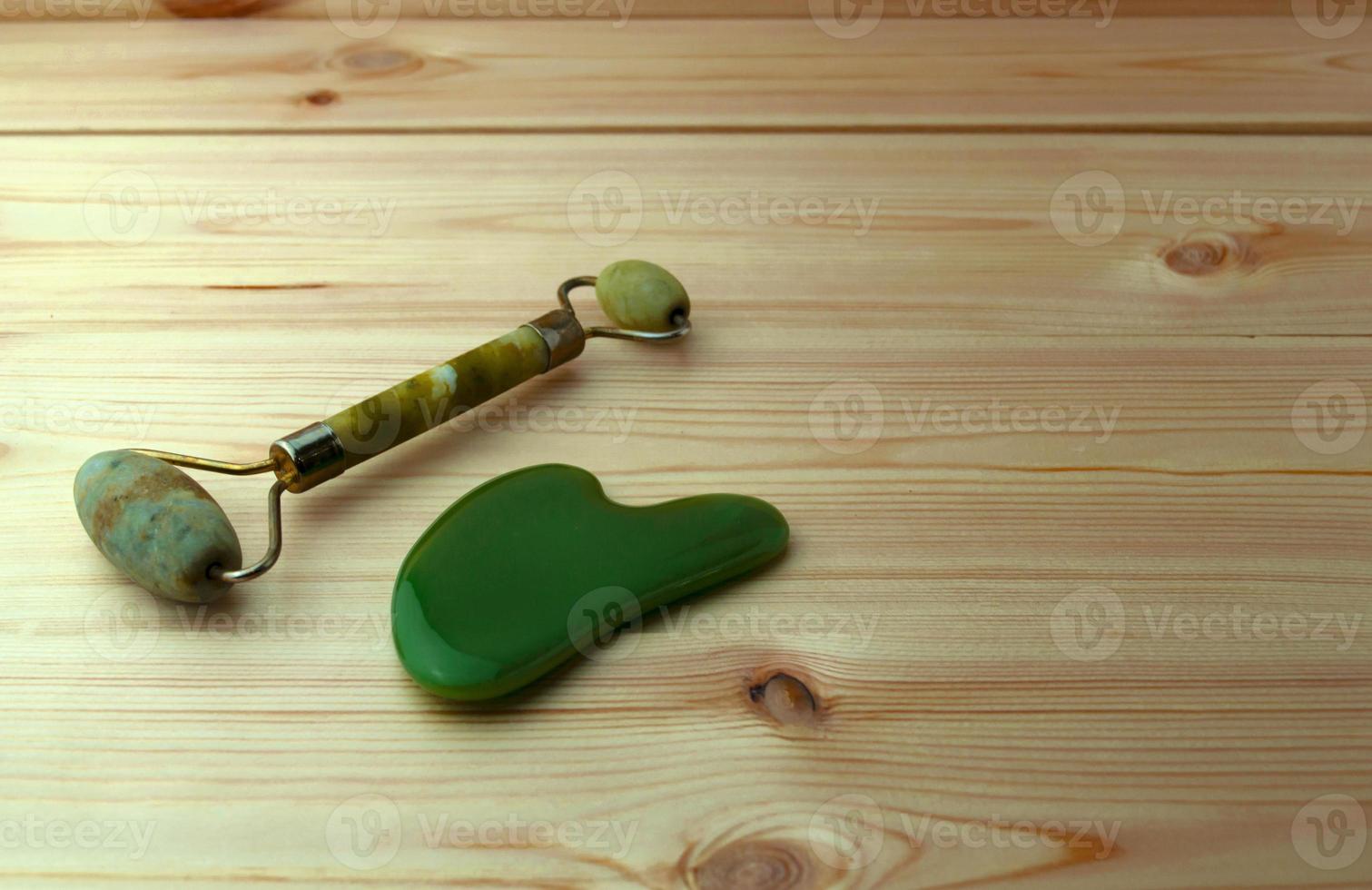 Jade roller and gouache scraper on a wooden table. photo