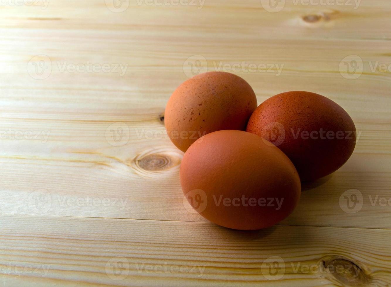 Three eggs on a wooden table. photo
