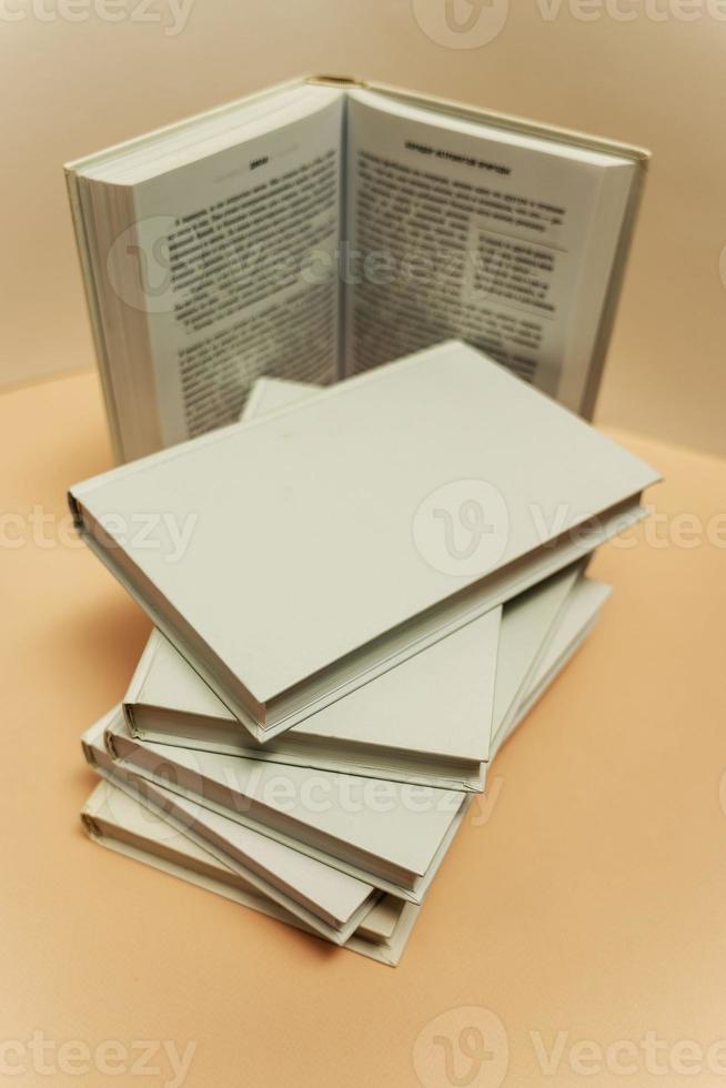 a stack of books on the table on a light pink background, study, back to school, library photo