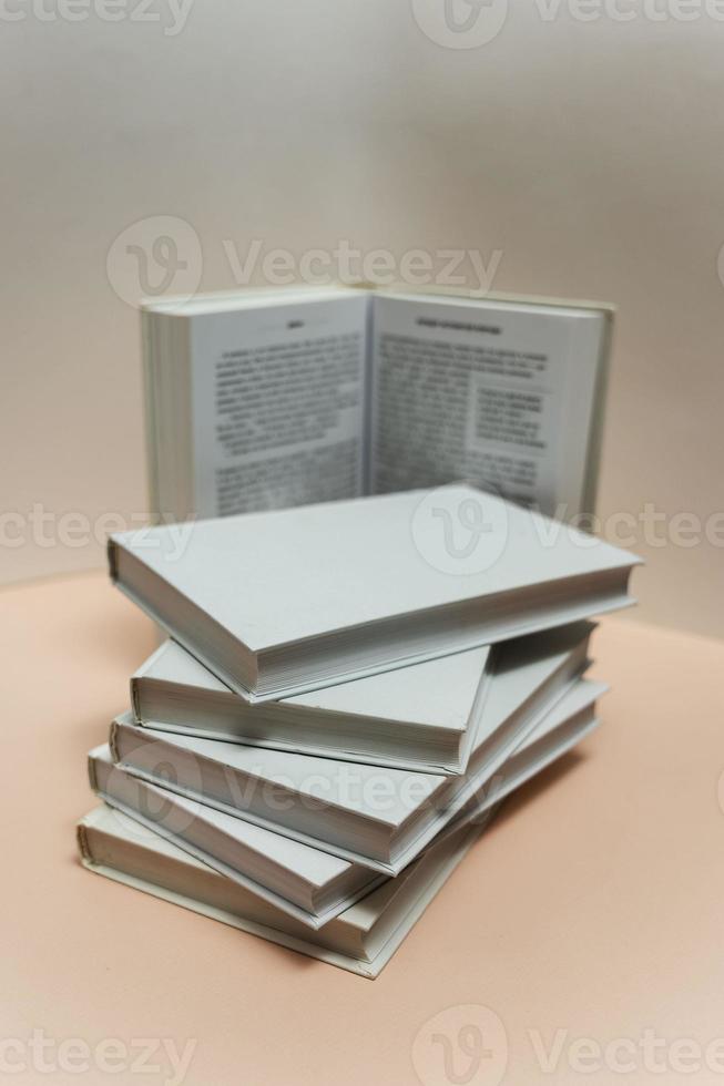 a stack of books on the table on a light pink background, study, back to school, library photo