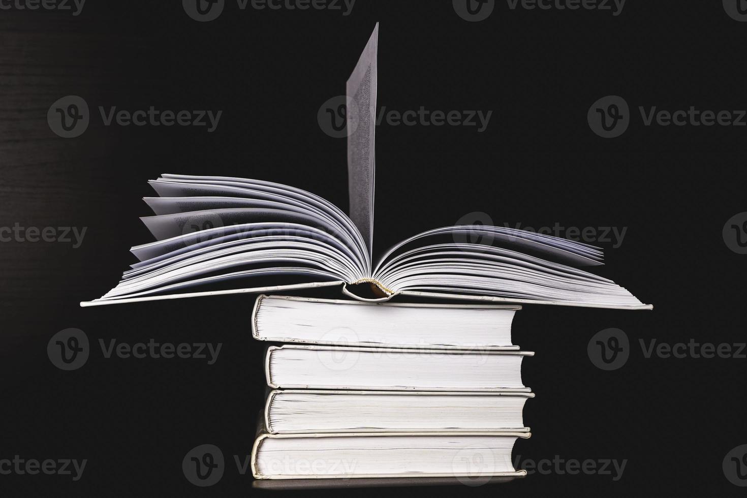 A stack of white blank books on a shelf on a black background, free space for copying, without labels, an empty spine. photo