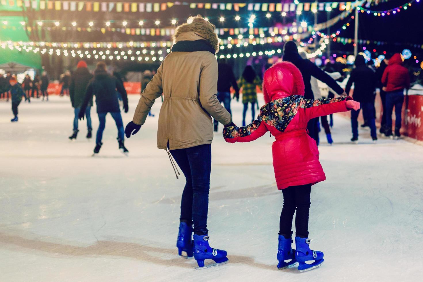 Happy family outdoor ice skating at rink mother and daughter has winter activities mom kids photo