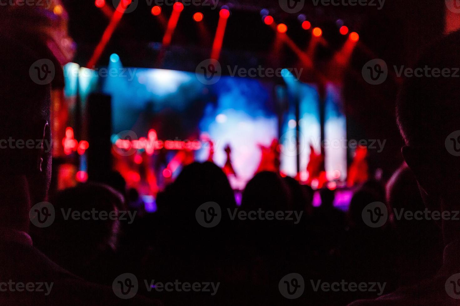 toma de algunos fanáticos que animan durante un concierto en vivo, ruido visible debido a iso alto, enfoque suave, dof poco profundo, ligero desenfoque de movimiento foto