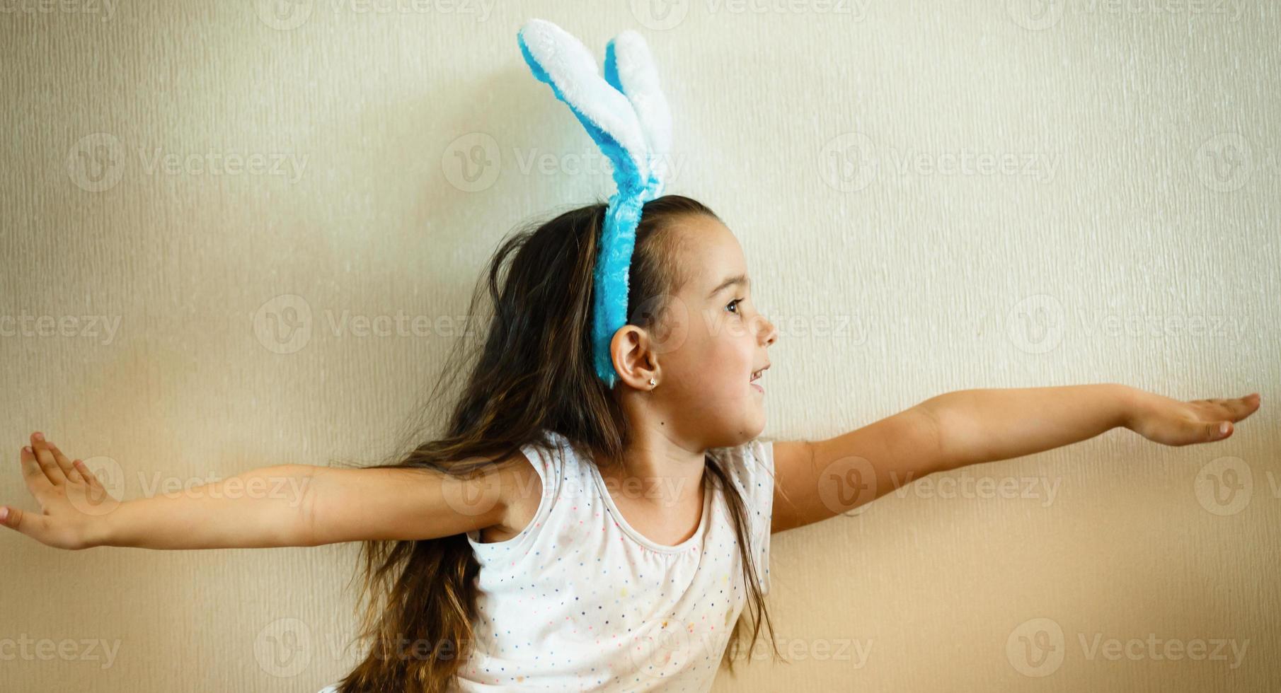 Portrait of a happy little girl with bunny ears looking up at copyspace isolated on a white background photo