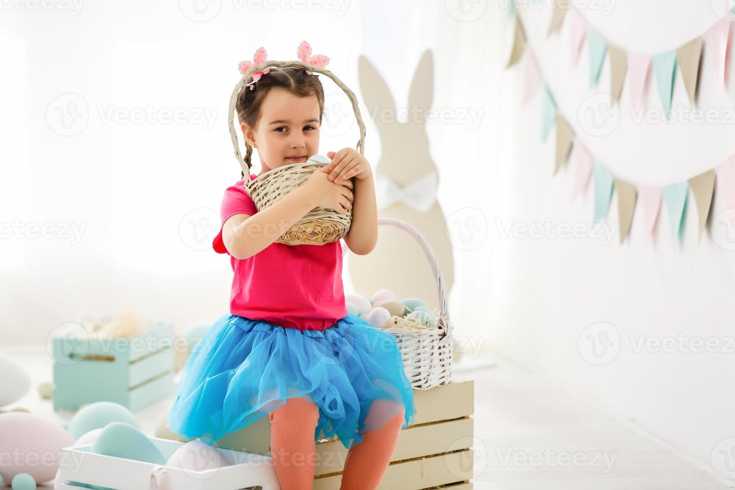 Getting ready to Easter. Lovely little girl holding an Easter egg and smiling with decoration in the background photo