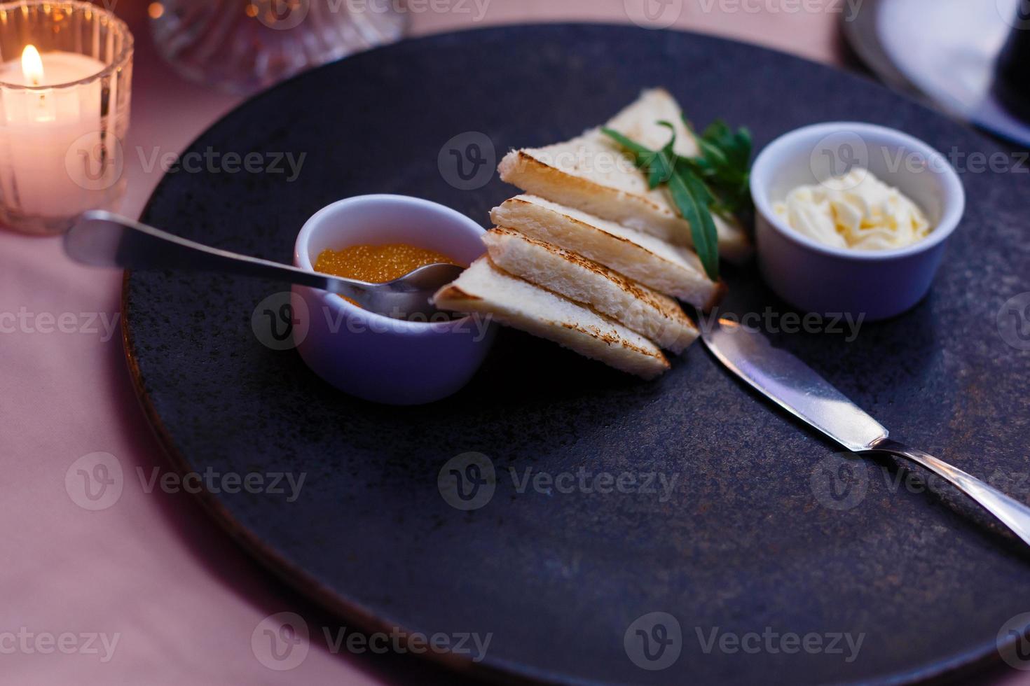 aperitivos comida para picar - plato negro, rectangular con canapés de caviar rojo, mantequilla foto