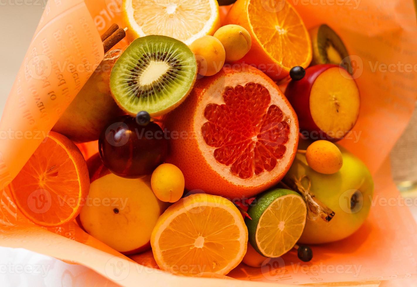 Bouquet of flowers and fresh citrus fruits wrapped in coarse paper in hands photo