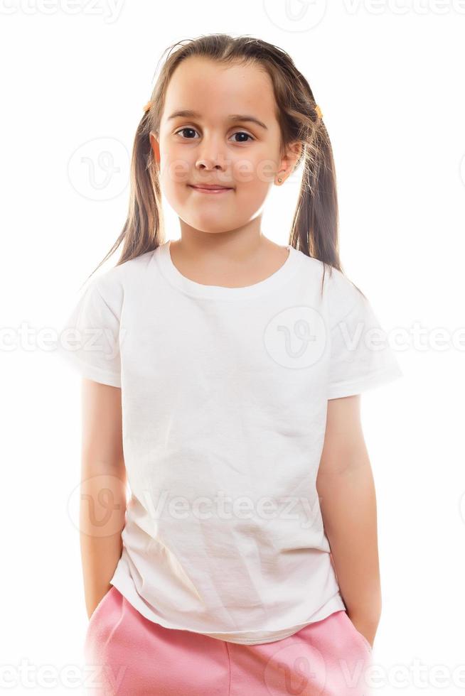 una niña positiva con una camiseta blanca informal indica un espacio en blanco para el diseño del logotipo foto