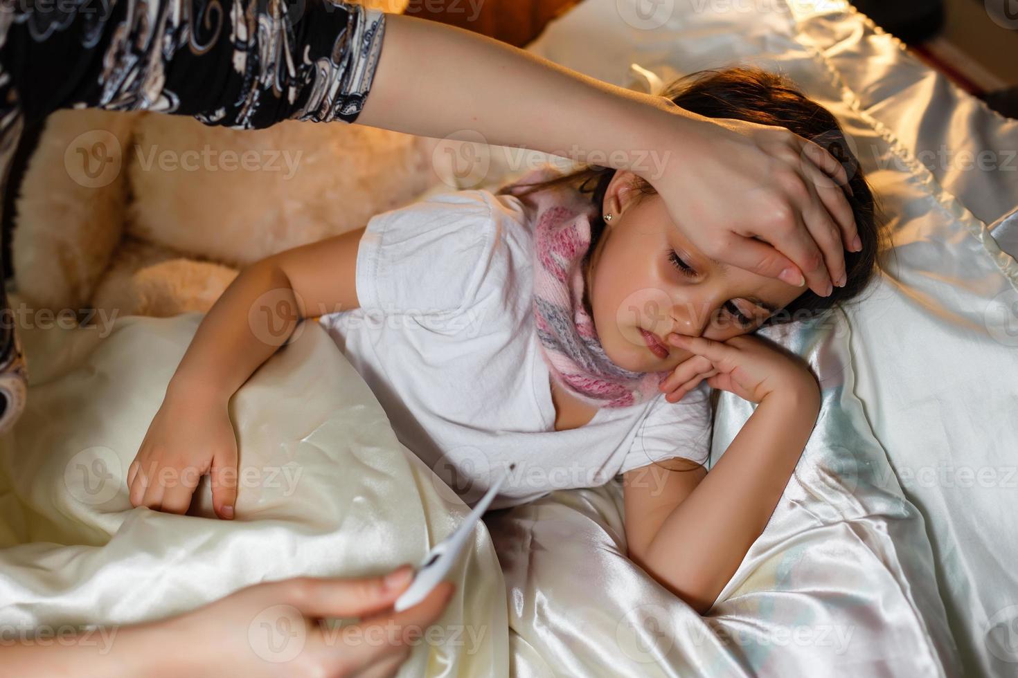 Close up of mother measuring temperature of her ill kid son sick child with high fever laying in photo