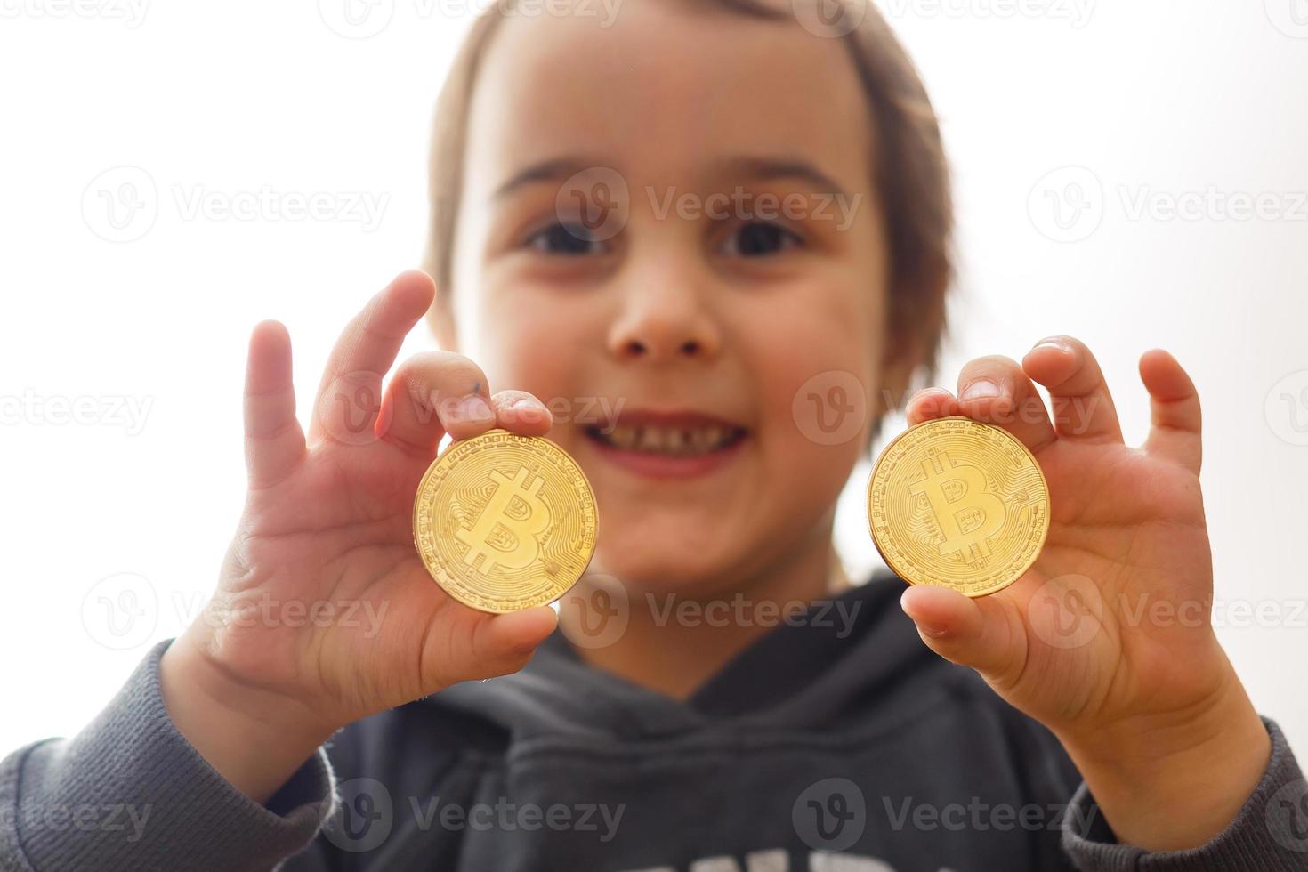 Smiling young girl holding two gold bitcoins in her hands thinking about crypto currency photo