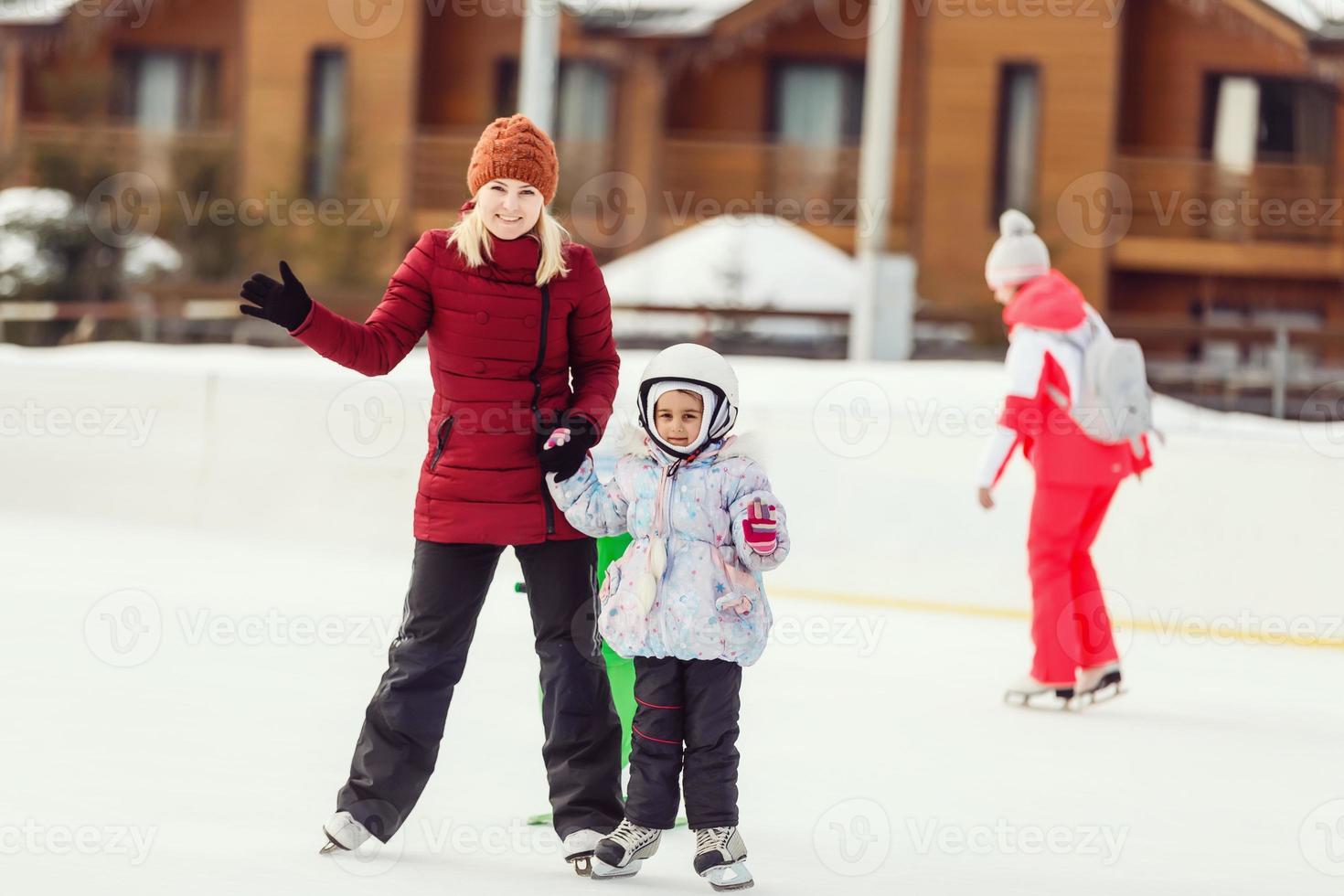 Mother and daughter having fun while skating at ice rink photo