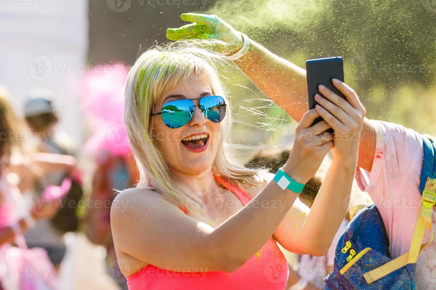 Portrait of happy young girl on holi color festival using mobile phone photo