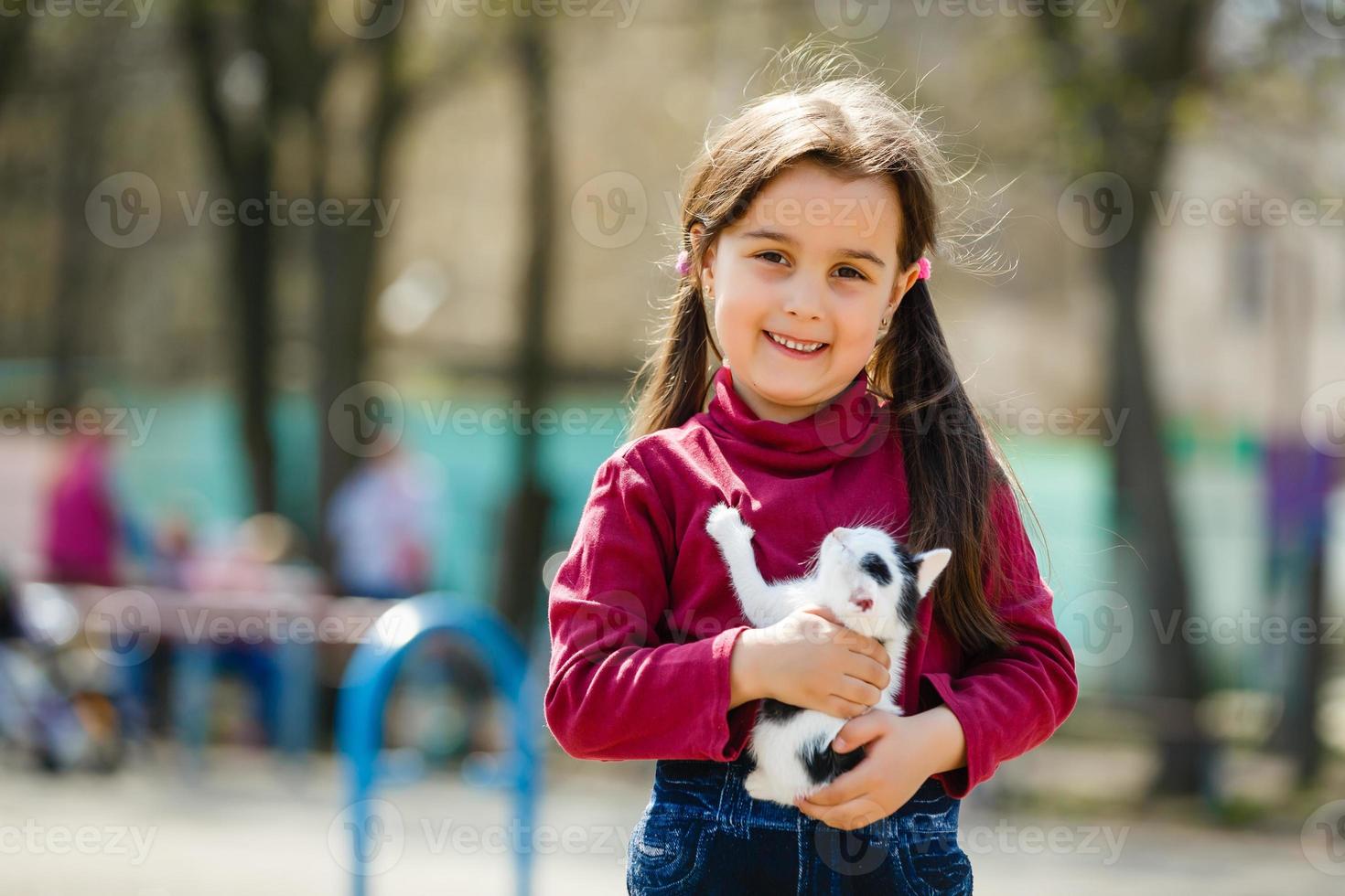 retrato al aire libre de una niña pequeña con un gatito pequeño, una niña jugando con un gato de fondo natural foto