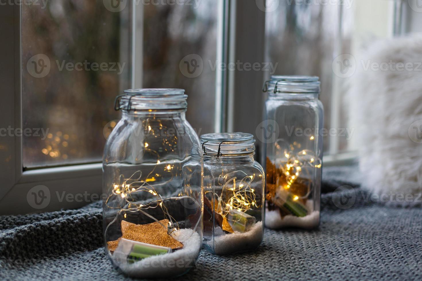 Beautiful lights, garland in a jar with textile red plush hearts and rose petals on a wooden background. Love or valentine's day concept photo