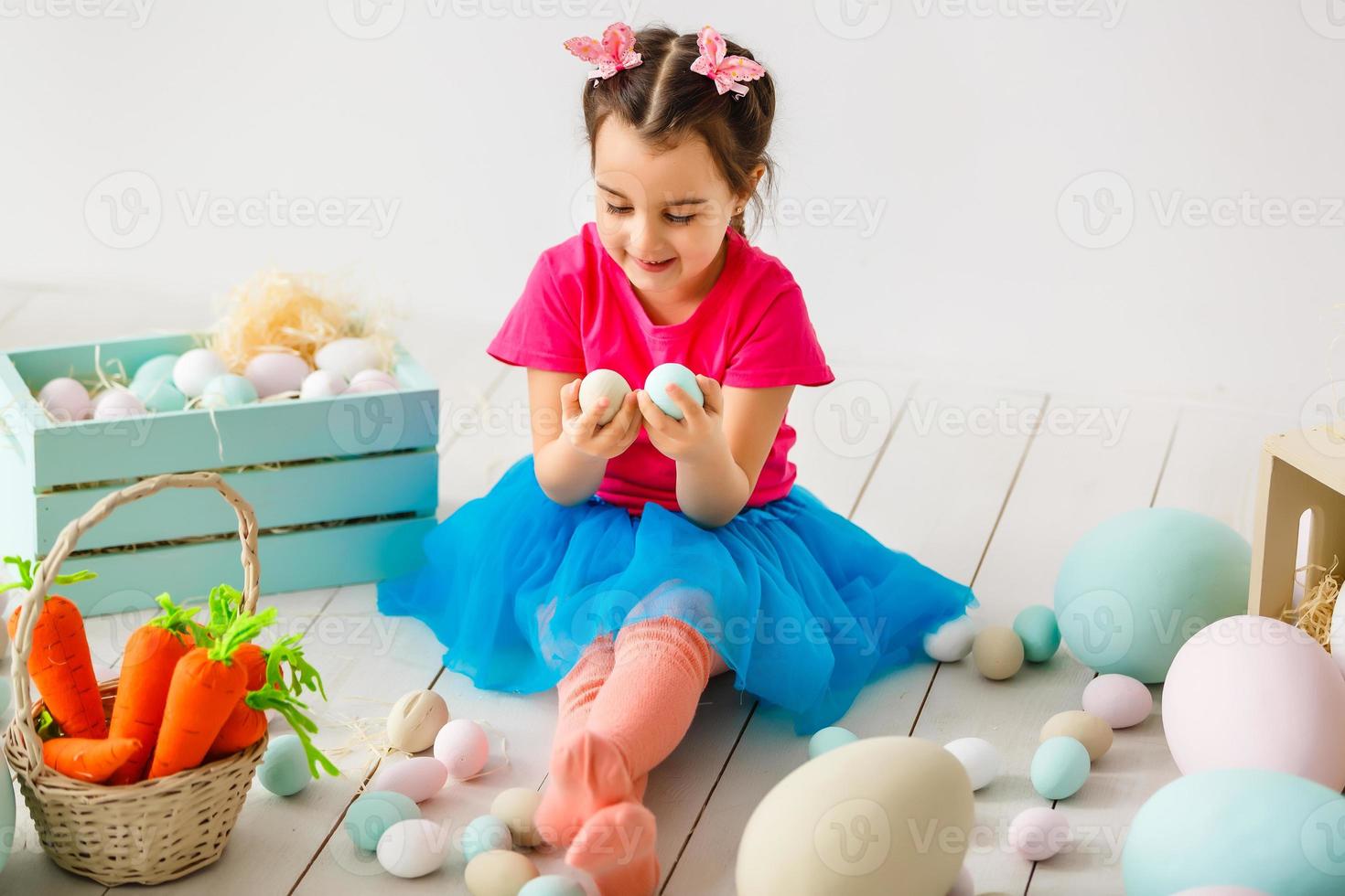 Getting ready to Easter. Lovely little girl holding an Easter egg and smiling with decoration in the background photo