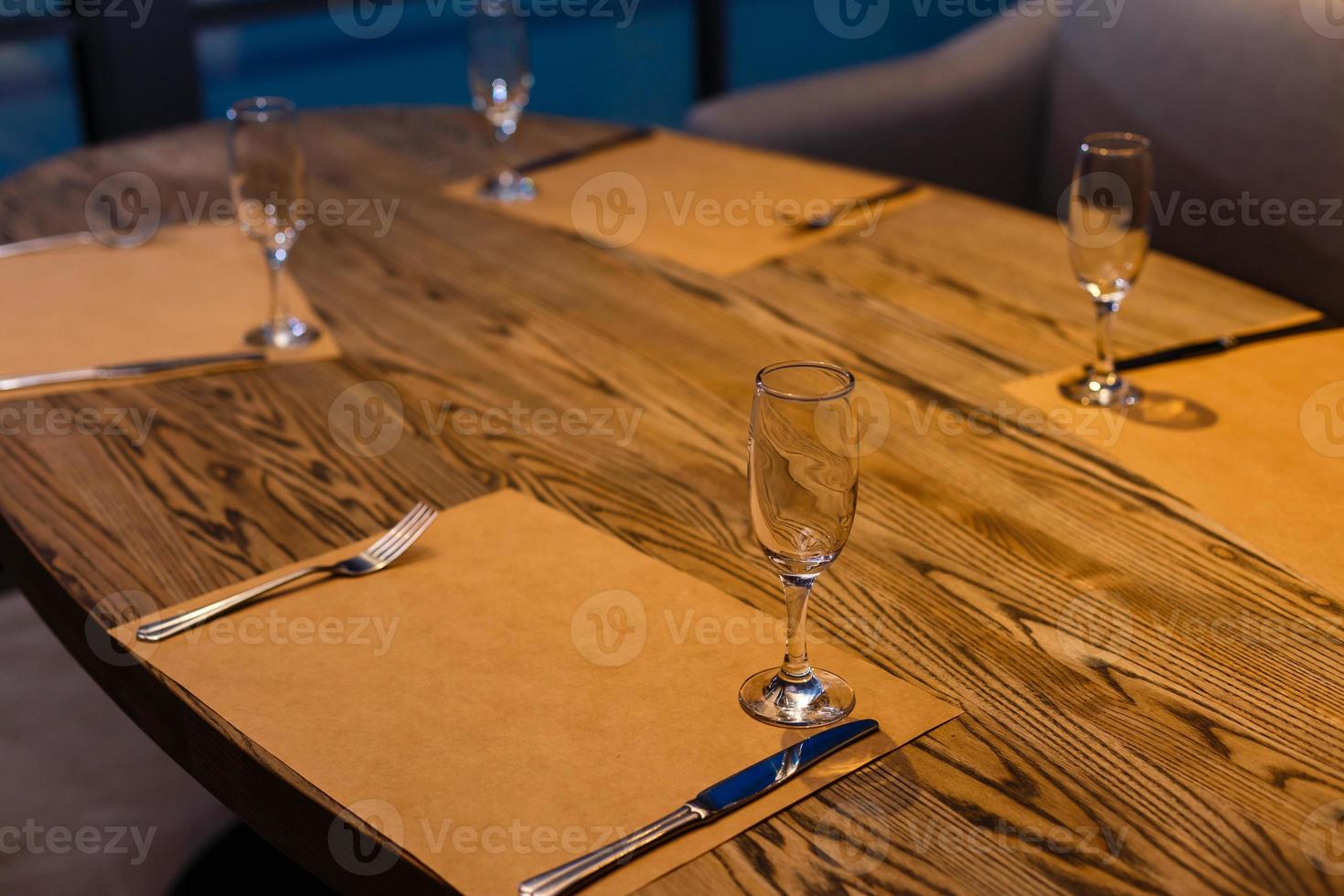 Glasses, forks, knives, plates on a table in restaurant served for dinner photo