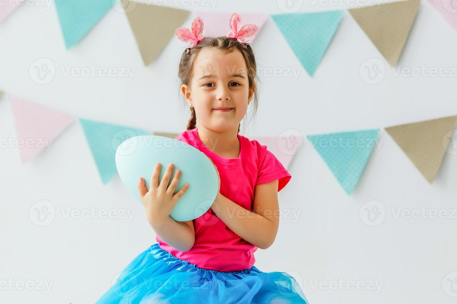 felices pascuas una hermosa niña pintando huevos de pascua. familia feliz preparándose para pascua. linda niña pequeña con orejas de conejo el día de pascua. foto