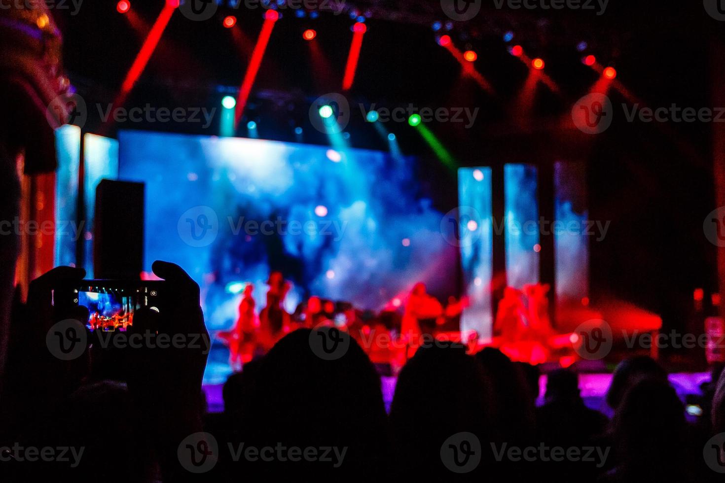 Shot of some cheering fans during a life concert, visible noise due high ISO, soft focus, shallow DOF, slight motion blur photo