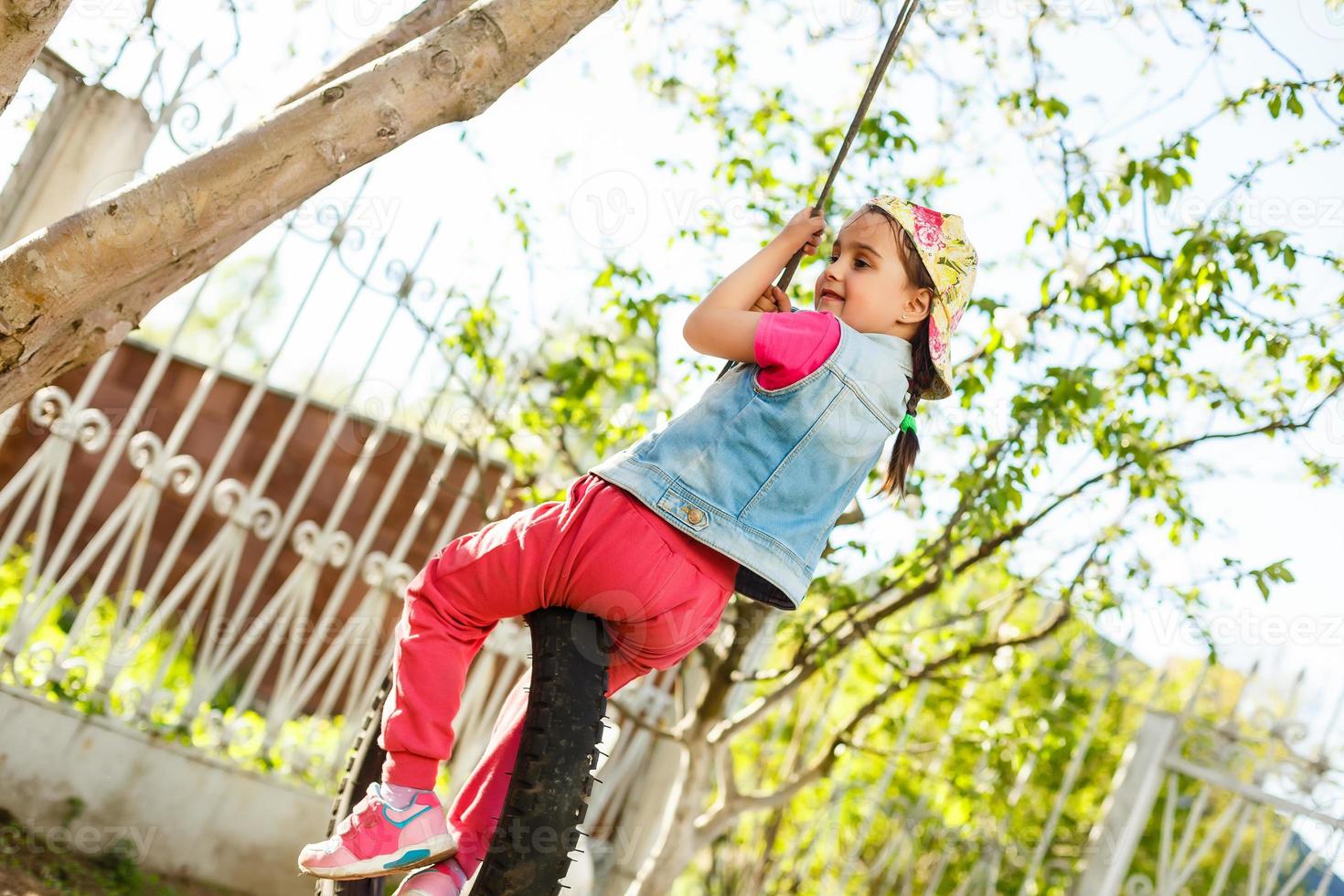 Happy Llittle girl playing swing at park photo