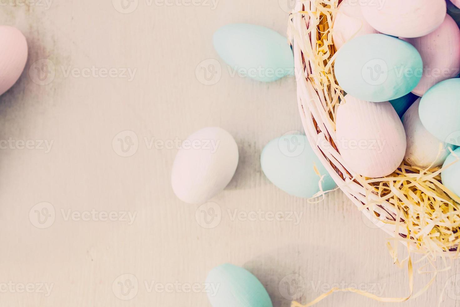 Easter eggs in nest on color wooden background photo