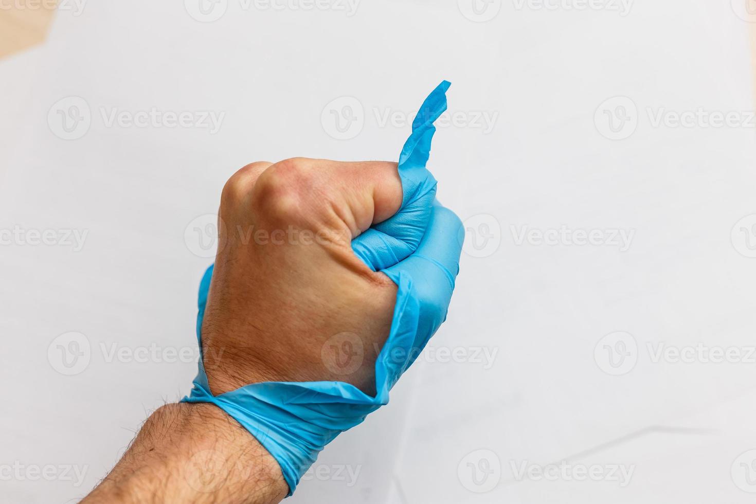 Hand wearing torn plastic protective glove photo