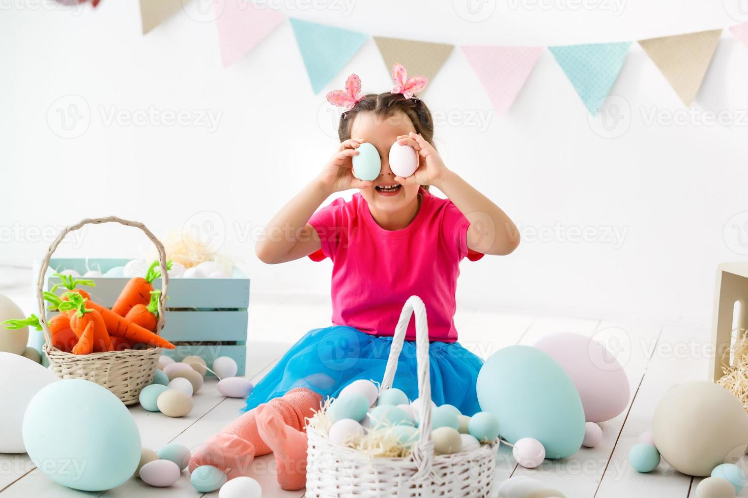 Getting ready to Easter. Lovely little girl holding an Easter egg and smiling with decoration in the background photo