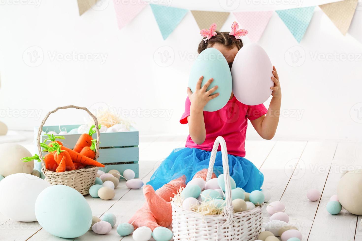 Getting ready to Easter. Lovely little girl holding an Easter egg and smiling with decoration in the background photo