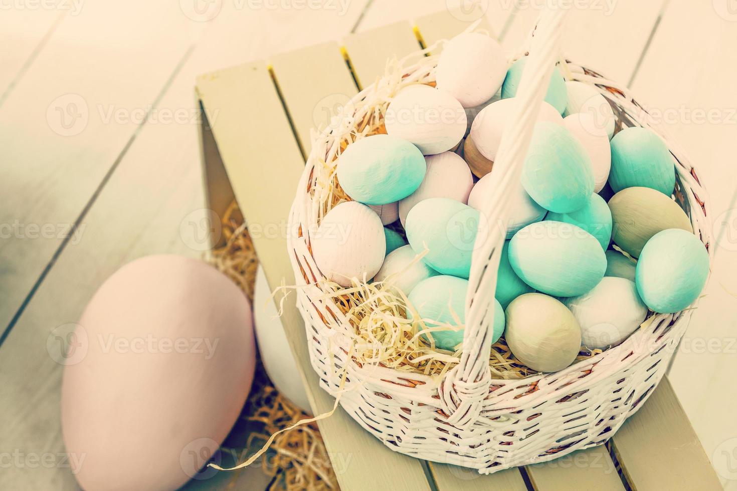 Easter eggs in nest on color wooden background photo