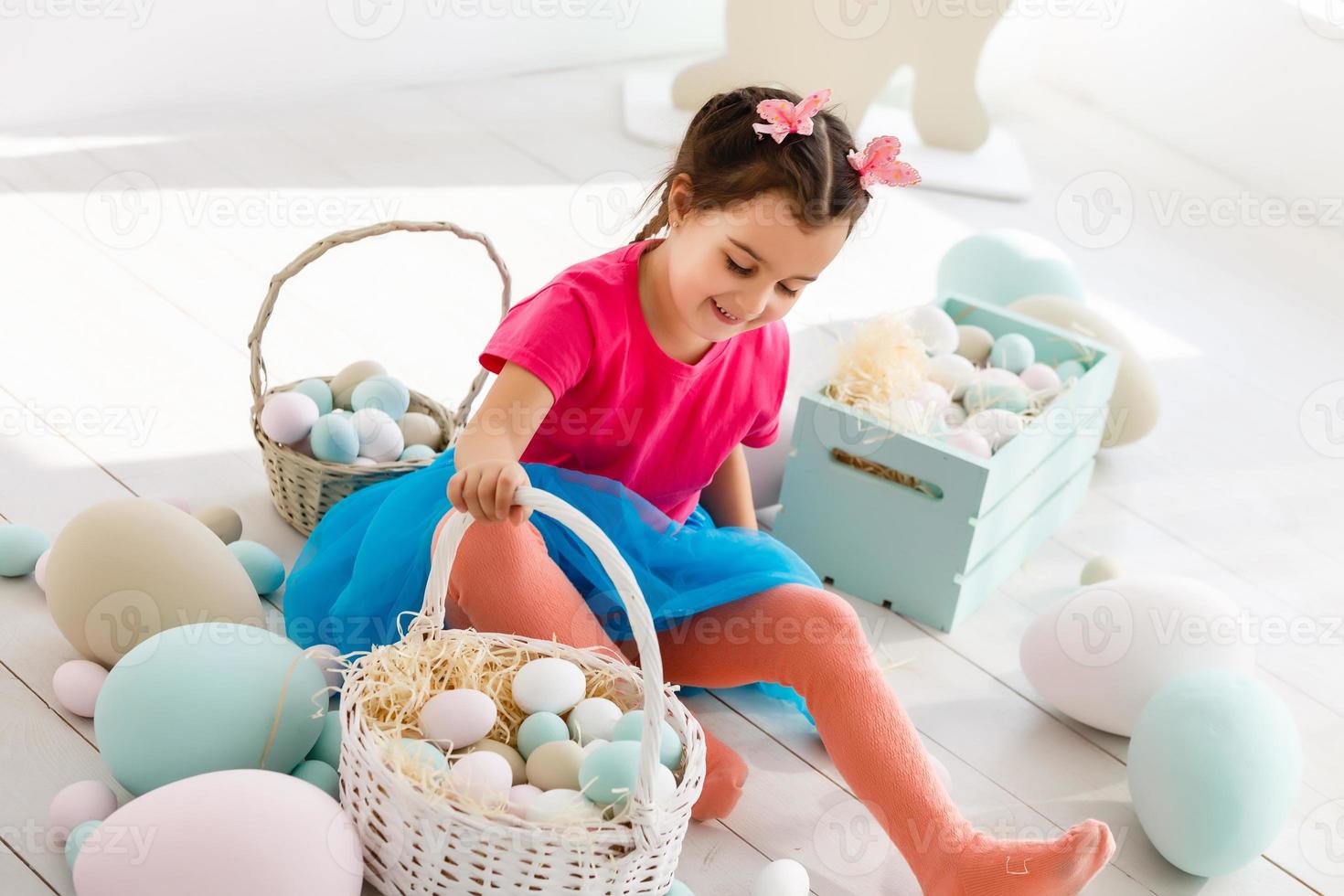 Getting ready to Easter. Lovely little girl holding an Easter egg and smiling with decoration in the background photo