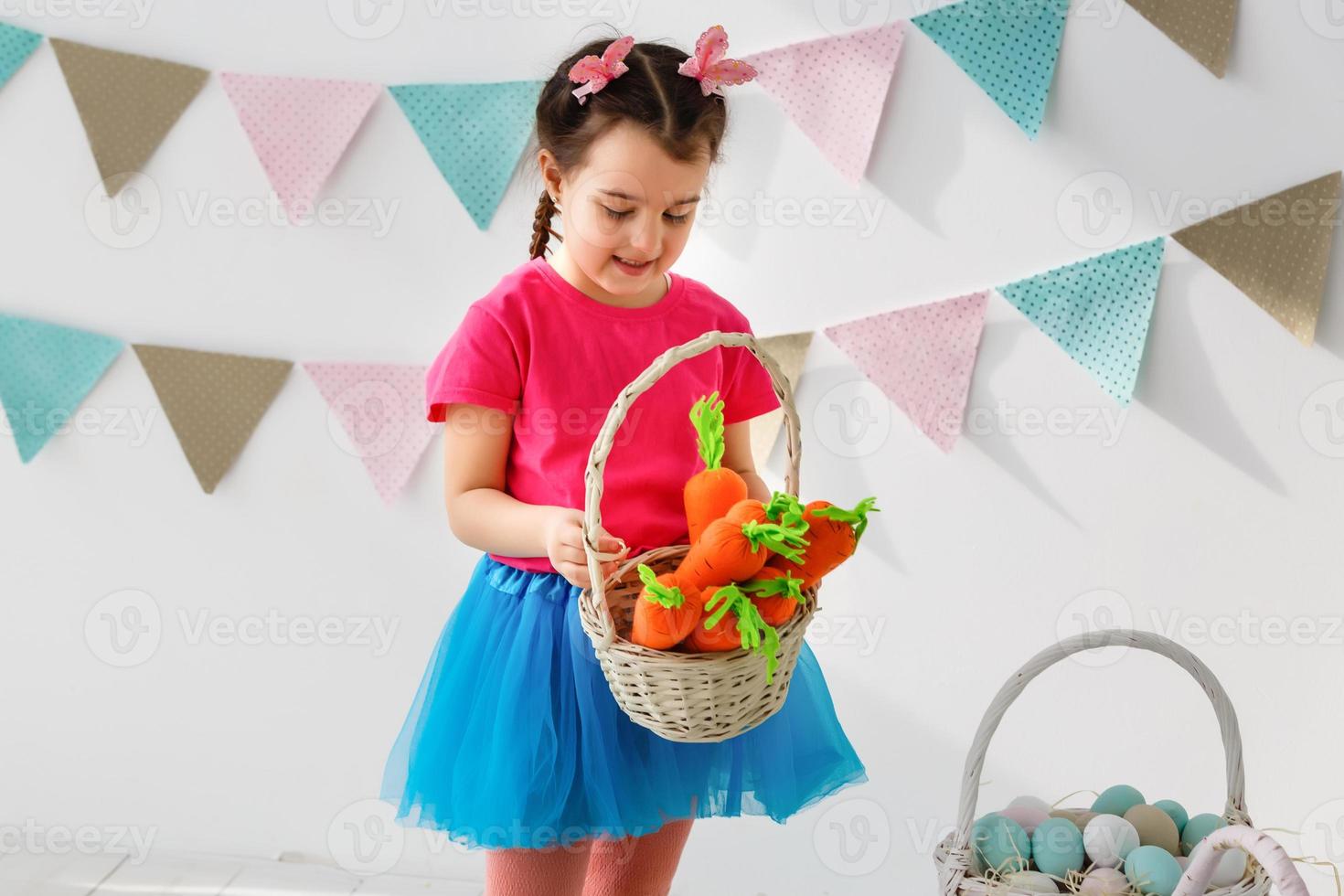 Getting ready to Easter. Lovely little girl holding an Easter egg and smiling with decoration in the background photo