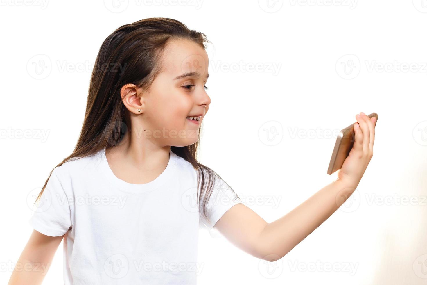 la niña está mirando la caricatura en el teléfono móvil en el concepto de fondo de la pared blanca foto