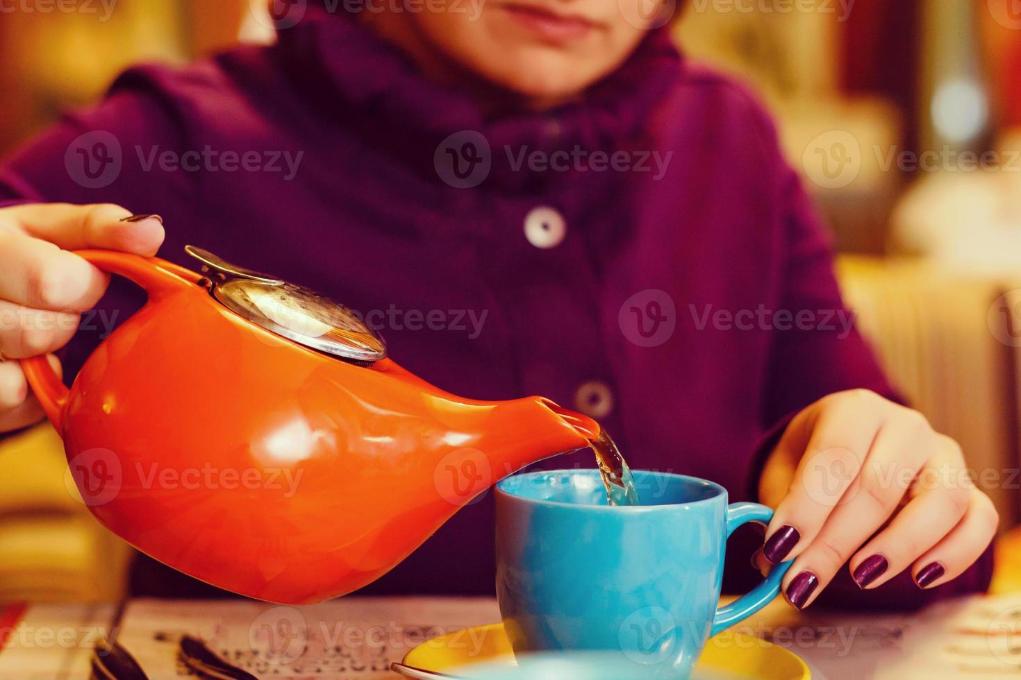 Closeup woman in a cafe pours tea, Teapot and Teacup. photo