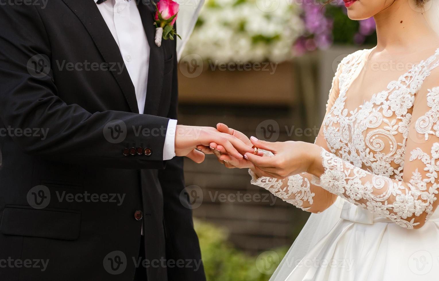 recién casados intercambiando anillos, novia poniendo el anillo en la mano del novio en la oficina de registro de matrimonio foto