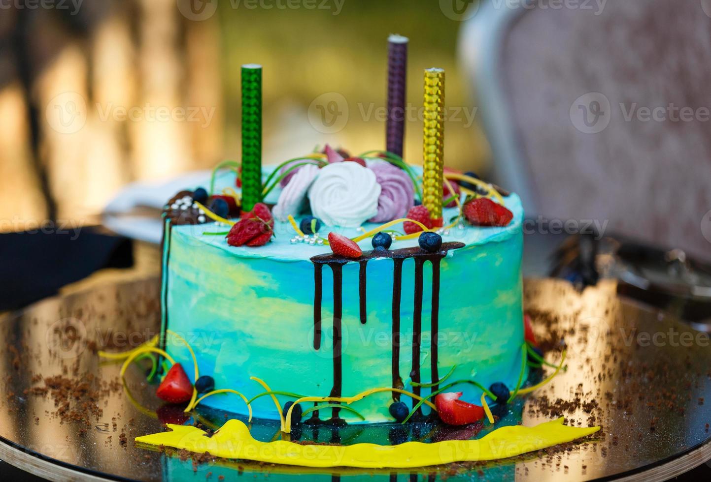 Blue buttercream birthday cake with colorful sprinkles over yellow background. photo