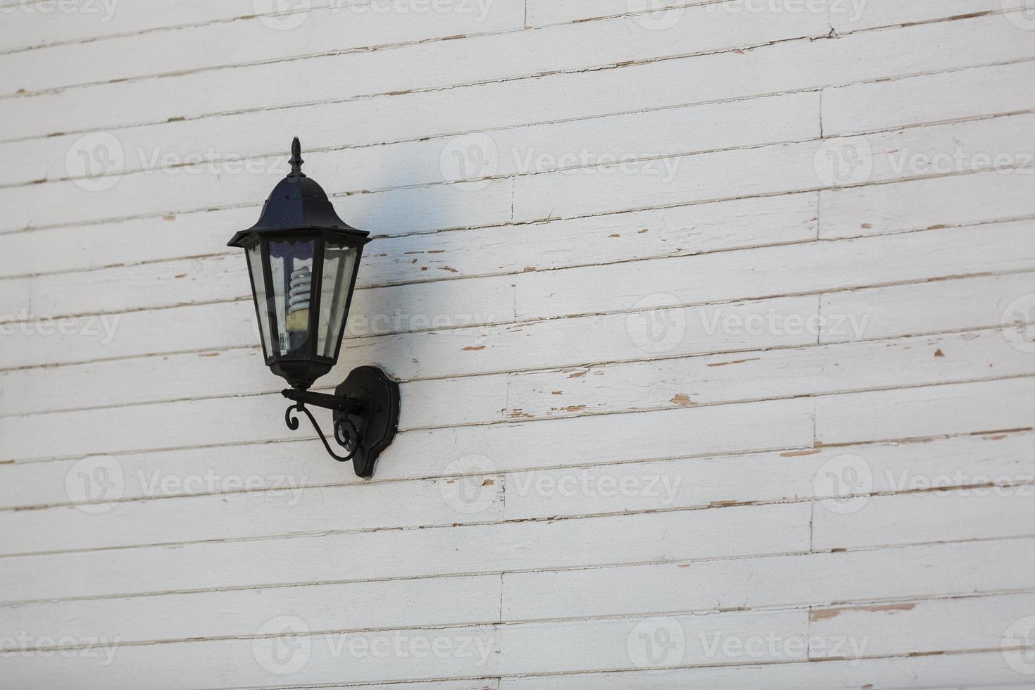 Lantern in the snow on a gray wooden wall. photo