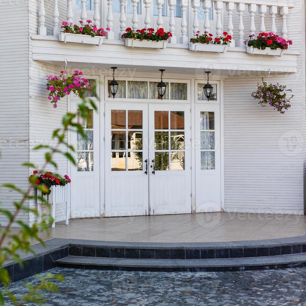 White front door with small square decorative windows and flower pots photo
