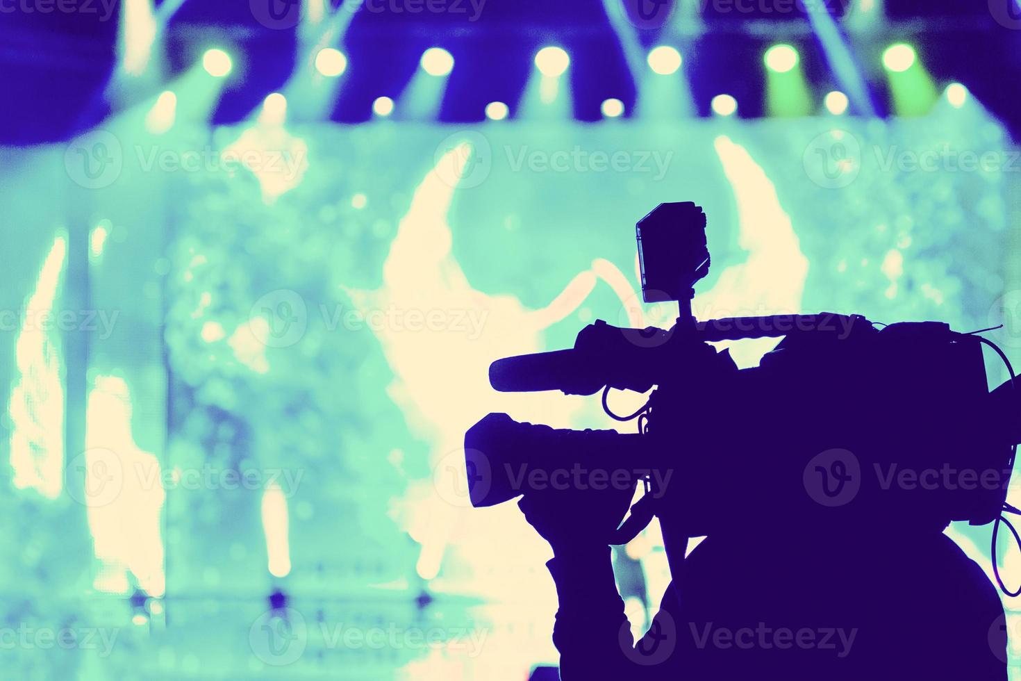 Professional Video camera operator working with his equipment, blue background photo