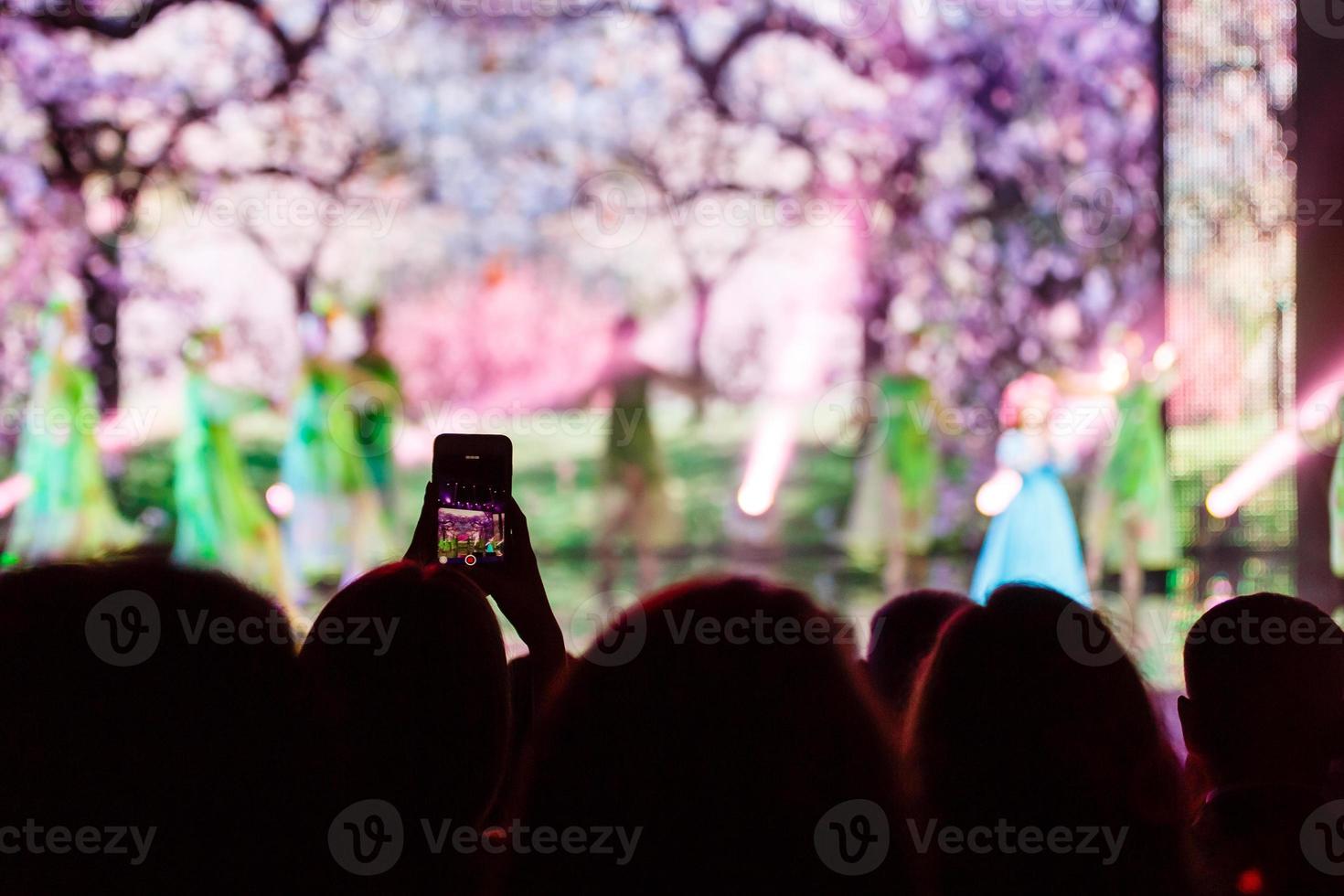 A smartphone held with two hand in order to shoot a footage during a concert. photo