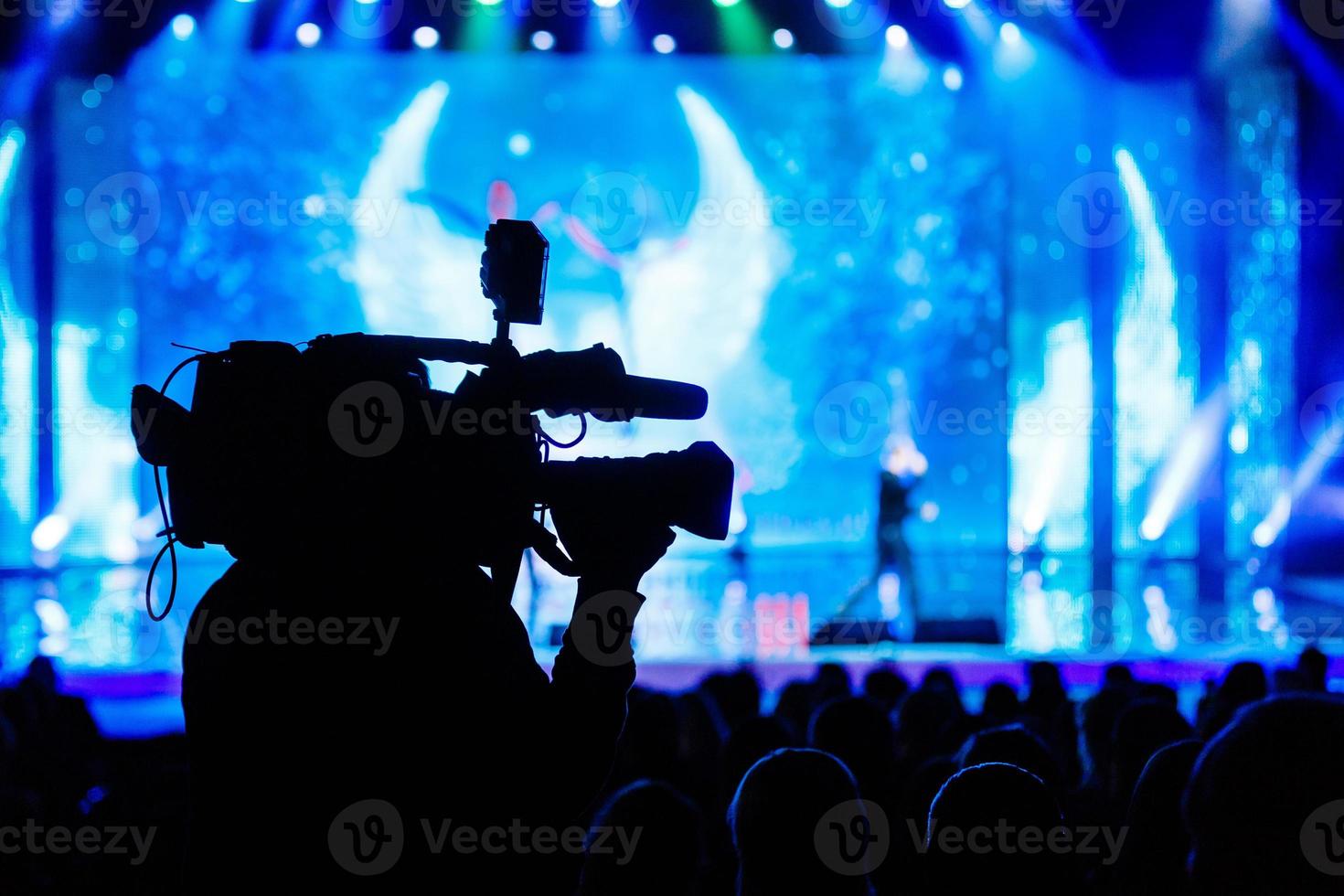 Professional Video camera operator working with his equipment, blue background photo