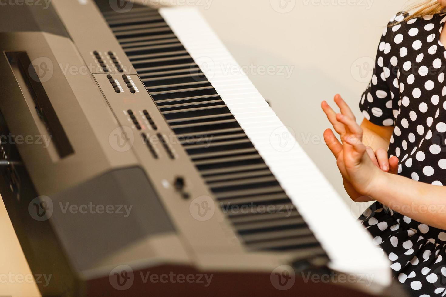 little girl learns to play the piano photo