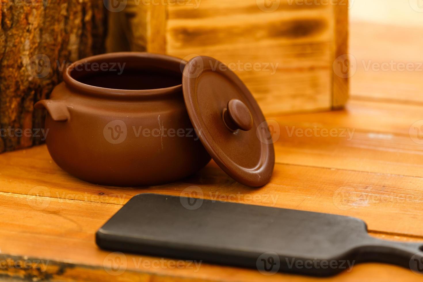 Dirty ceramic pot on old wooden kitchen board photo