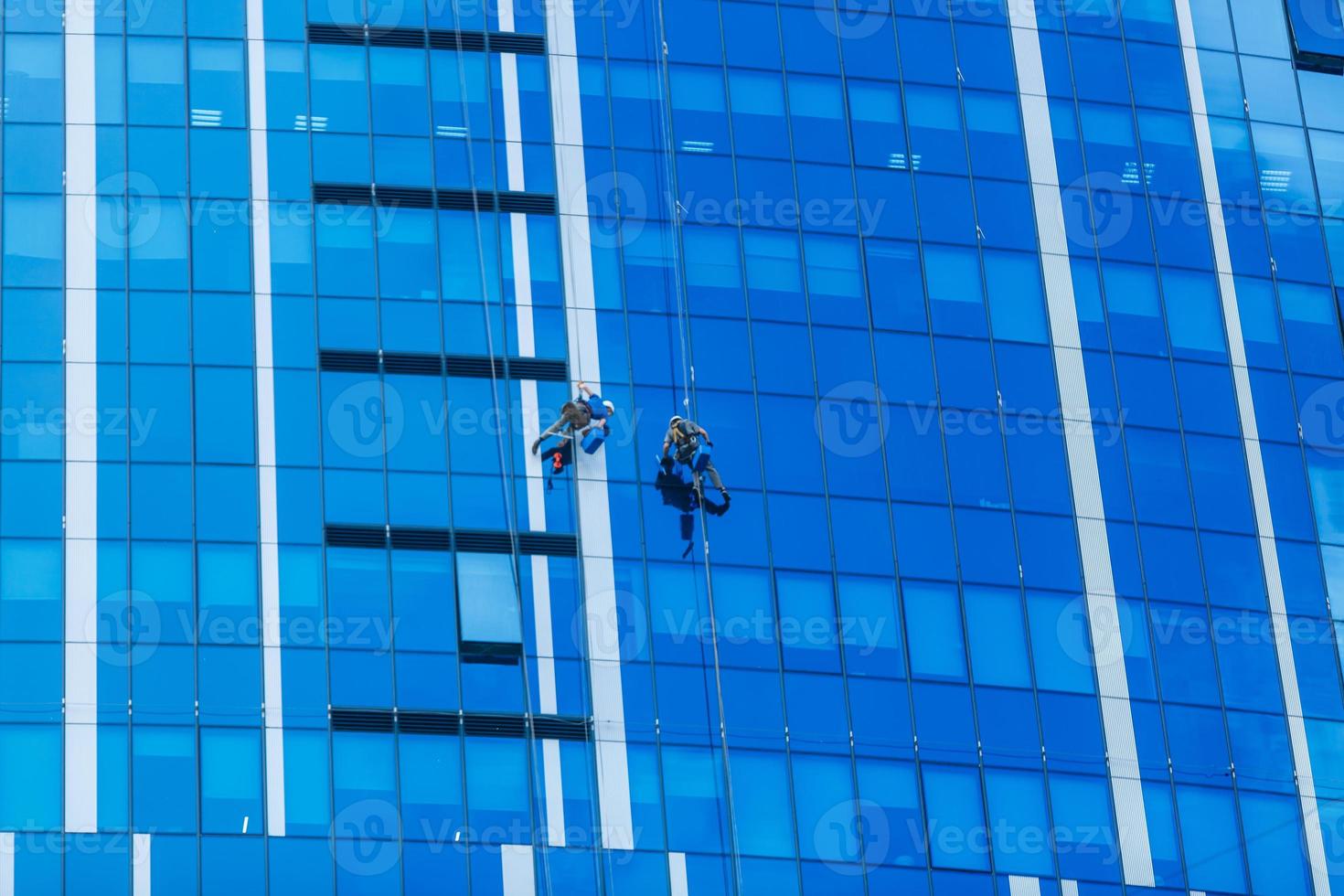 Two workers washing windows of the modern building. photo