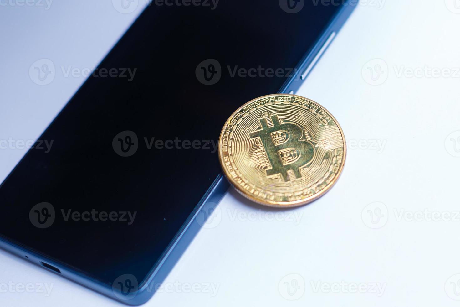 A bitcoin and smart phone on a white isolated surface photo