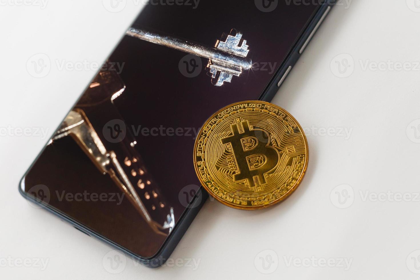 Gold bitcoin cryptocurrency with a smartphone on a wooden table photo