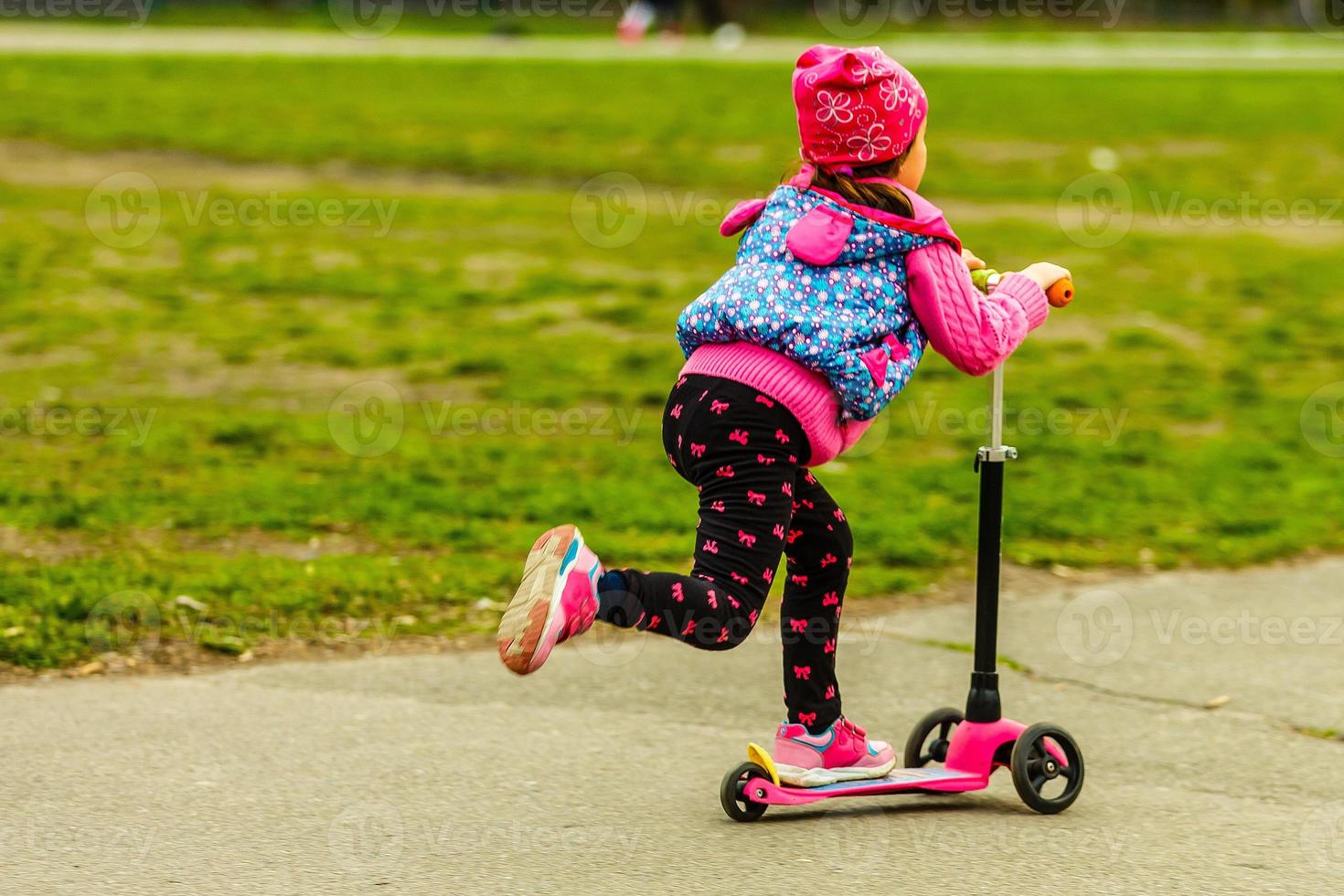 Little girl using a scooter on a countryside road photo