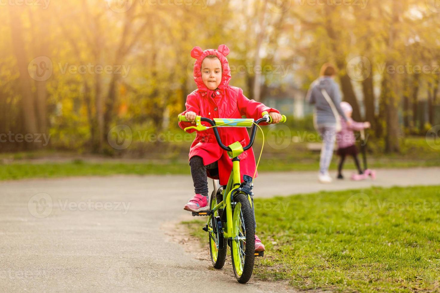 Beautiful smiling little girl riding bicycle in a park photo
