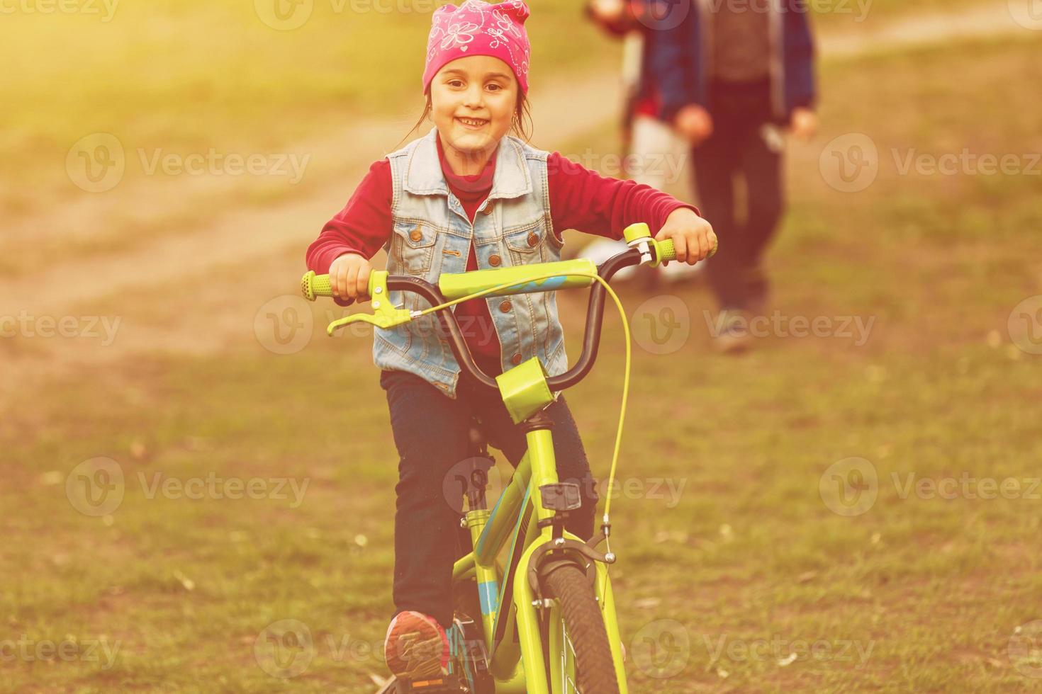 Little girl riding bike at sunset photo