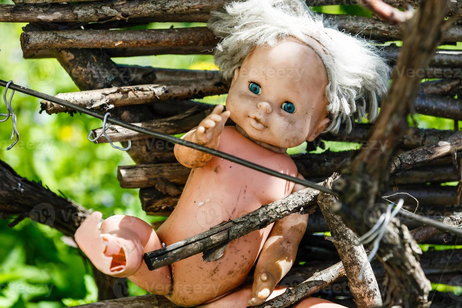 Una vieja y abandonada muñeca rota se pudre en un bosque aterrador foto