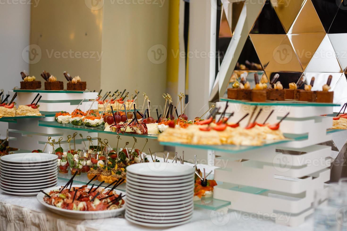 Beautifully decorated catering banquet table with burgers profiteroles salads and cold snacks photo