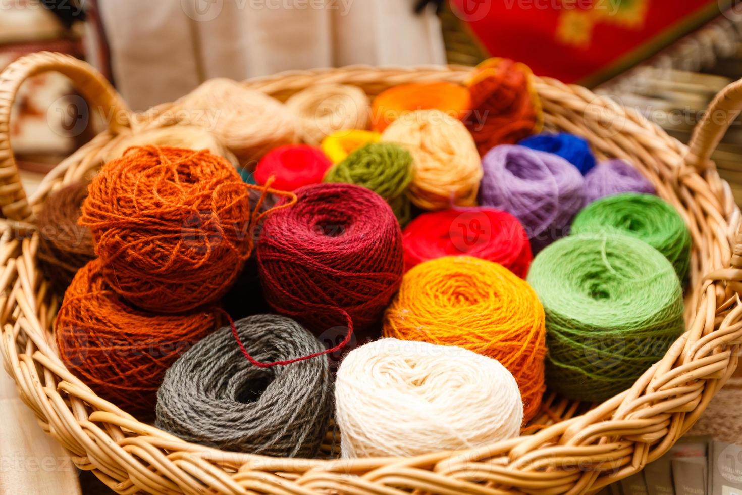 Balls of yarn scattered near the basket lots of colorful threads on old background yarns photo